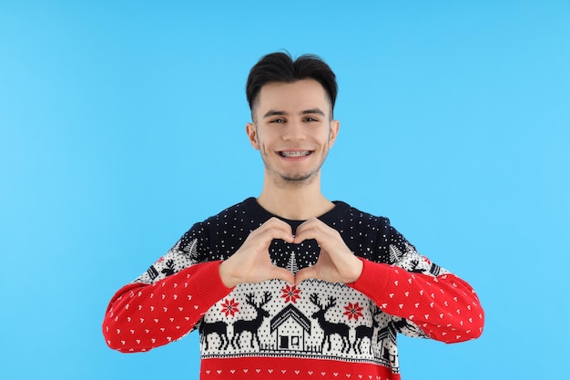 Mec séduisant en pull de Noël sur fond bleu