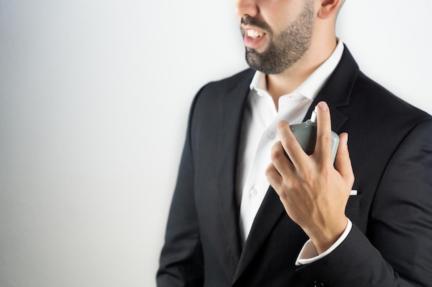 Un mec souriant et élégant avec une barbe qui applique de l'eau de Cologne en spray