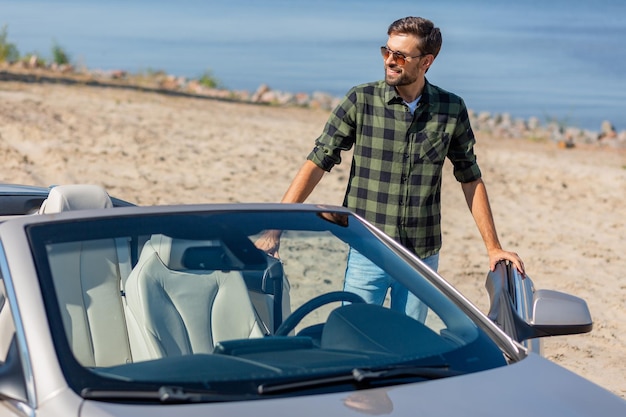 Un mec souriant ouvre la porte du cabriolet pour s'asseoir