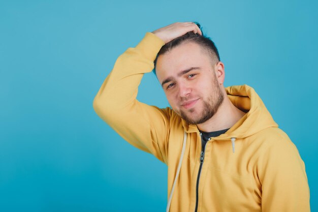 mec sportif dans un pull jaune sur fond bleu