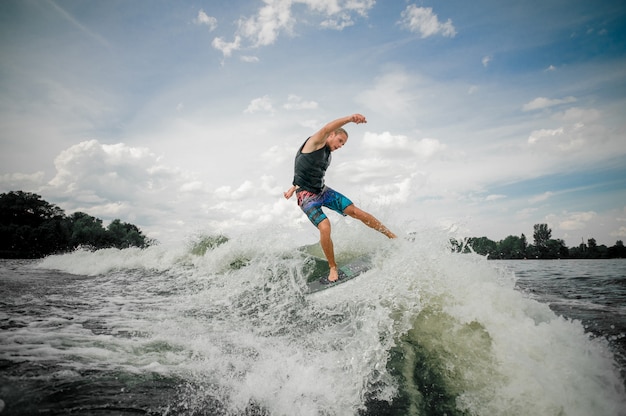 Mec sportif faisant du surf sur la planche en bas de la rivière contre le ciel