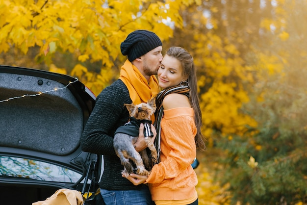 Un mec tient un chien mignon dans ses bras et embrasse sa fille préférée