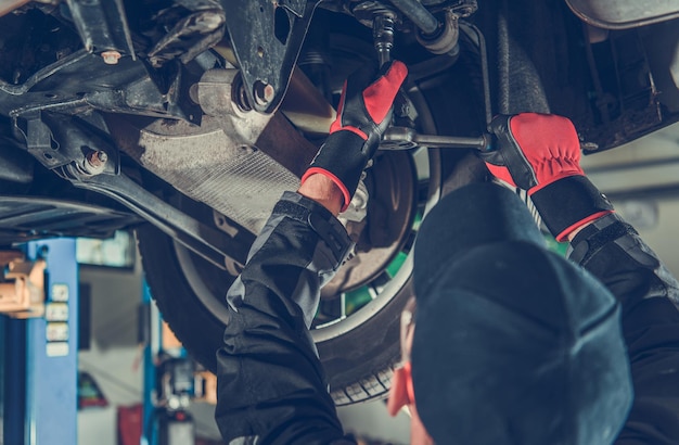 Mécanicien automobile caucasien travaillant sous un véhicule