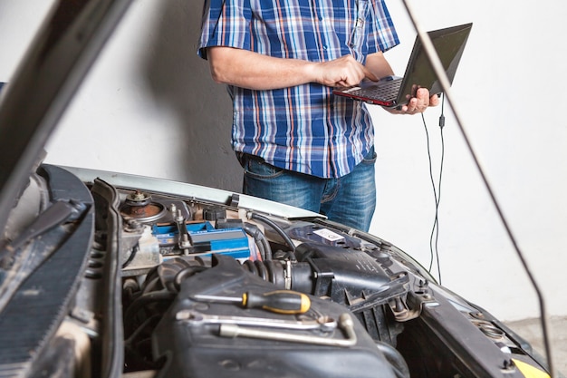 Mécanicien automobile avec une clé dans le garage faisant des réparations de voiture