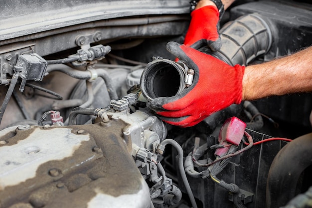 Le mécanicien automobile a déconnecté le tuyau d'air du moteur de la voiture Réparations de voitures