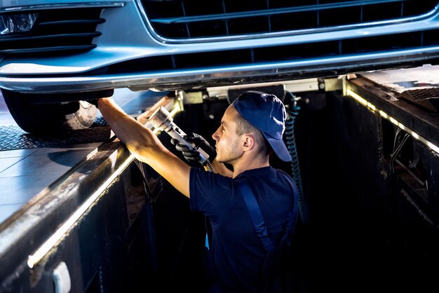 Mécanicien automobile examinant la suspension de voiture de voiture levée