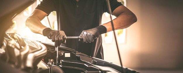 Mécanicien automobile gros plan à l'aide de la clé pour réparer le problème du moteur de voiture Concepts de contrôle et d'inspection Entretien et maintenance de la voiture