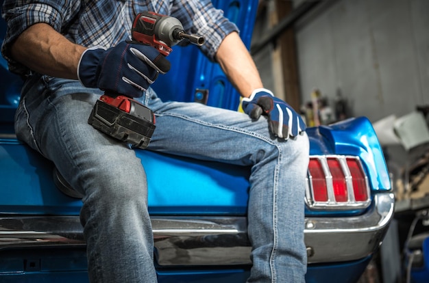 Mécanicien automobile avec Powertool sans fil dans sa main et son prochain projet