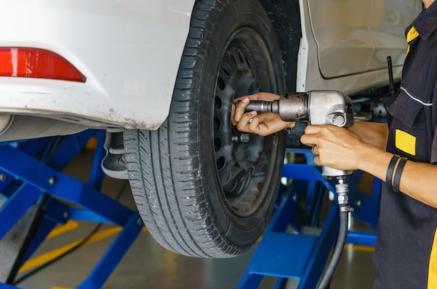 Mécanicien automobile professionnel changeant la roue de voiture dans le service de réparation automatique