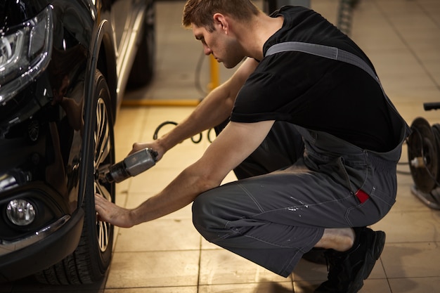 Un mécanicien automobile professionnel concentré répare une roue qui s'est cassée