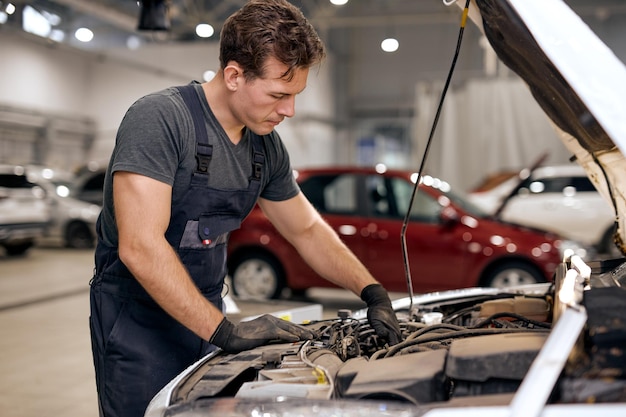 Mécanicien automobile regardant à l'intérieur du moteur dans le concept de problèmes et de solutions de réparation de moteur de voiture de garage youn