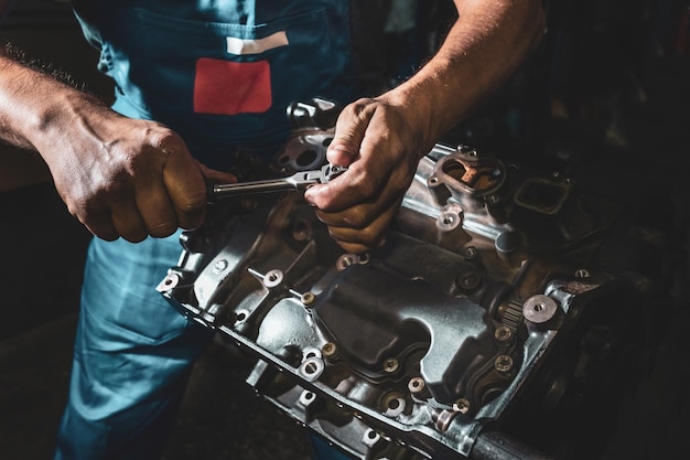 Mécanicien automobile réparant un moteur dans un garage sombre