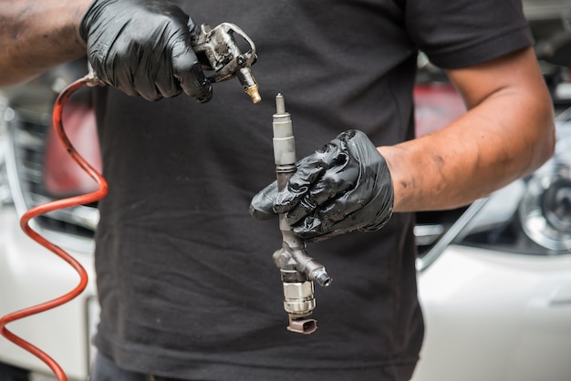 Un mécanicien automobile ou un technicien démontage un moteur sale de la voiture pour nettoyer l&#39;injection de carburant