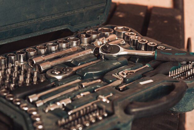 Le mécanicien automobile tient dans sa main une clé et des passages sur le fond d'une planche avec des outils pour réparer la voiture. Fermer. Garage de réparation de voiture