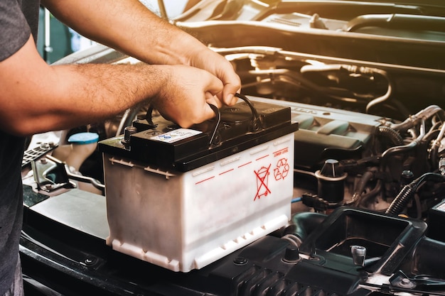 Un mécanicien automobile transporte une batterie de voiture de remplacement pour l'entretien électrique de la voiture