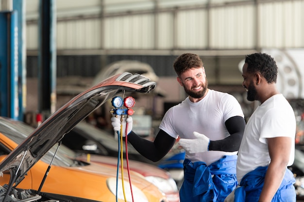 Photo mécanicien automobile travaillant dans un atelier de réparation automobile inspectant le fonctionnement du climatiseur de voiture