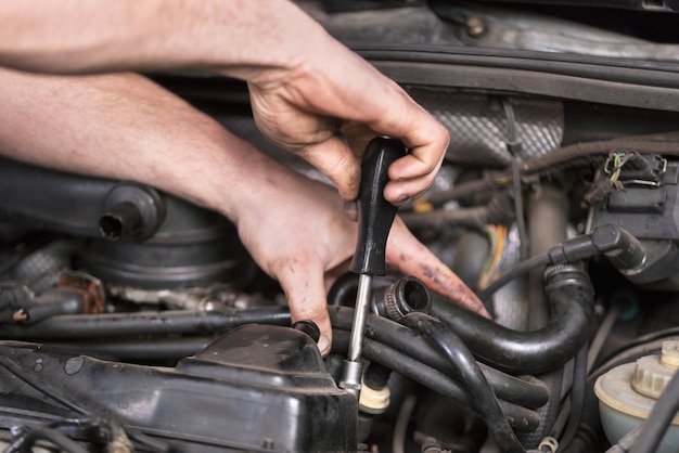 Mécanicien automobile travaillant sur le moteur de la voiture au service de réparation. Vue rapprochée.