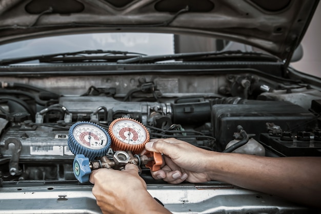 Mécanicien automobile utilisant un outil de mesure pour remplir les climatiseurs de voiture.