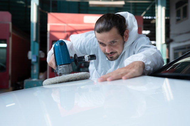 Un mécanicien automobile utilise une polisseuse électrique pour polir la peinture de voiture séchée Après avoir passé la peinture de la salle de peinture de voiture