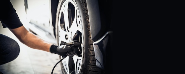 Mécanicien automobile vérifiant la pression d'air et gonflant les pneus de voiture