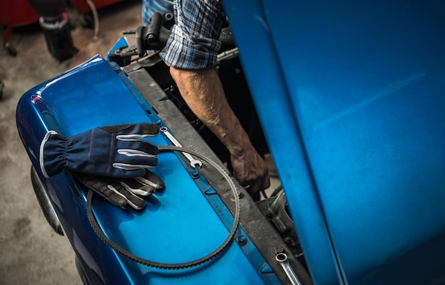 Mécanicien caucasien prenant soin d'un moteur de voiture classique