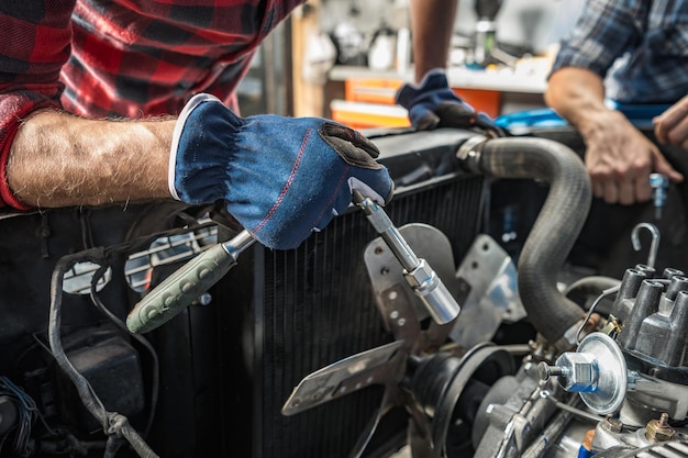 Mécanicien caucasien professionnel prenant soin d'un moteur de voiture classique