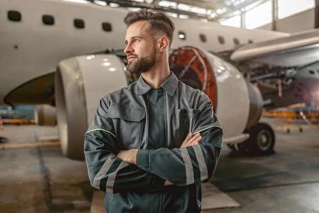 Mécanicien de compagnie aérienne homme barbu debout près de l'avion dans le hangar