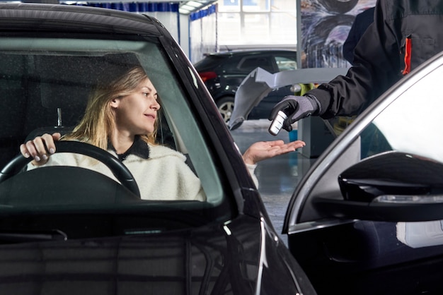 Mécanicien donnant des clés de voiture à une cliente après l'entretien