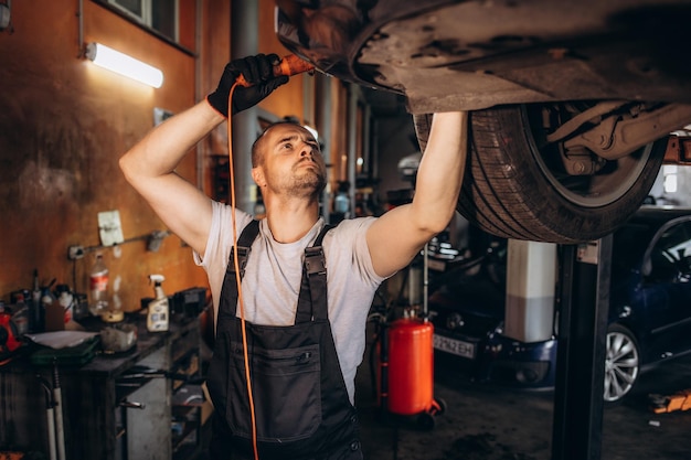 Un mécanicien examine un pneu de voiture à l'aide d'une lampe de poche dans le garage de réparation