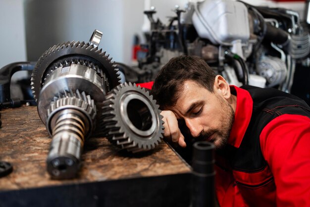 Photo mécanicien fatigué dormant au travail à l'intérieur de l'atelier