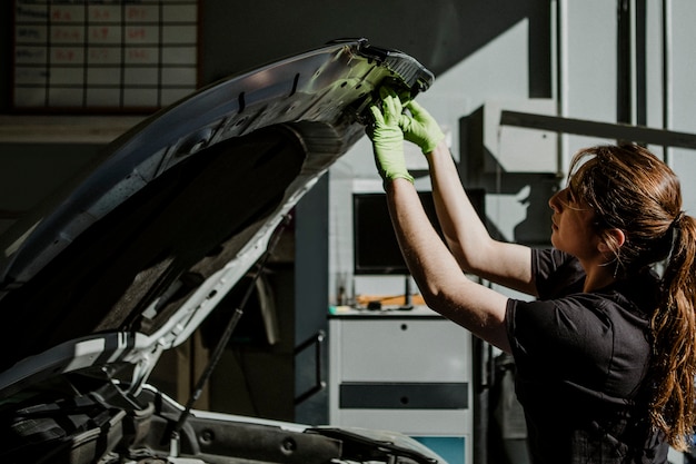 Photo mécanicien féminin ouvrant un capot de voiture