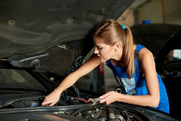 Mécanicien féminin réparant une voiture dans le garage