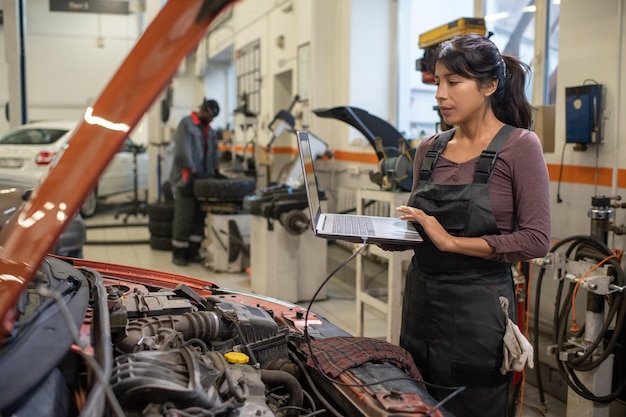 Mécanicien féminin vérifiant les erreurs du moteur