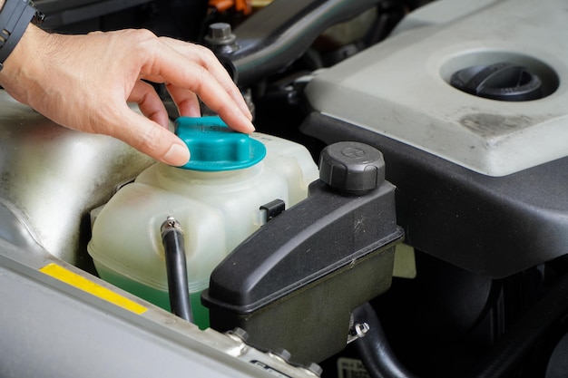 Le mécanicien inspecte le vase d'expansion avec de l'antigel vert Niveau de liquide de refroidissement du véhicule dans la voiture
