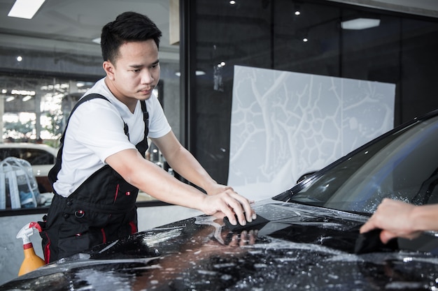 Le mécanicien installe un film de protection pour la peinture automobile.