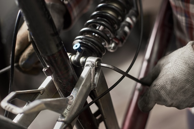 Mécanicien masculin faisant le service dans un atelier de réparation de vélos à l'aide d'outils