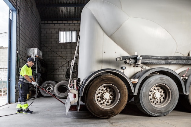 Mécanicien masculin sérieux utilisant un cric hydraulique pour soulever un camion dans le garage