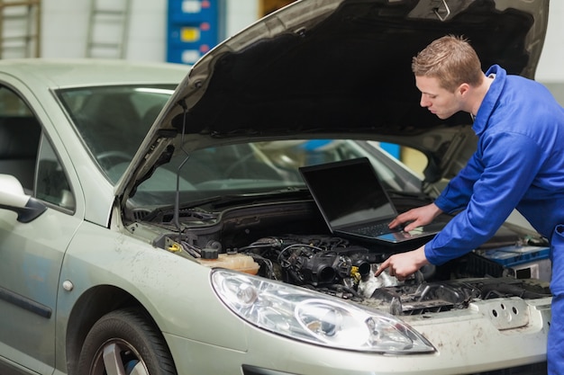 Mécanicien avec ordinateur portable vérifiant le moteur