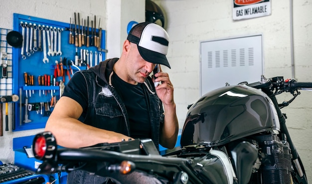 Mécanicien parlant au téléphone tout en réparant la moto