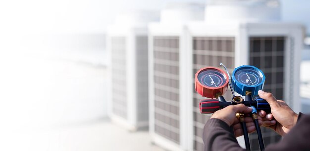 Mécanicien de réparation de l'air utilisant des équipements de mesure pour le remplissage des climatiseurs d'usine industrielle