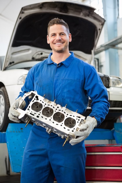 Mécanicien souriant tenant un moteur