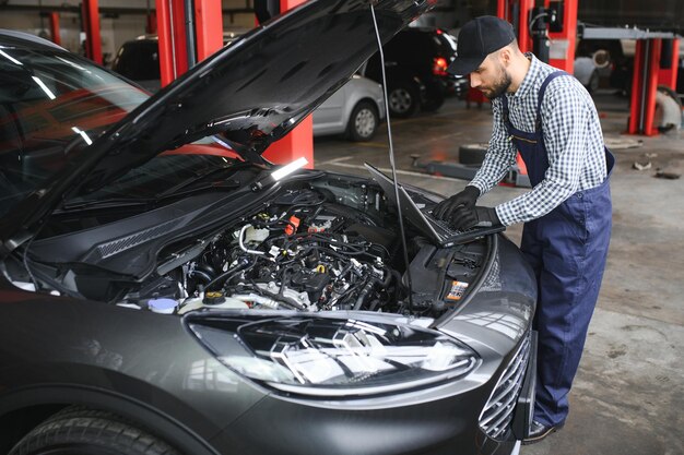 Mécanicien souriant utilisant un ordinateur portable au garage de réparation