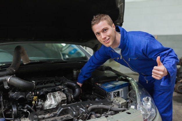 Mécanicien sous le capot de la voiture gesticulant pouce en l&#39;air