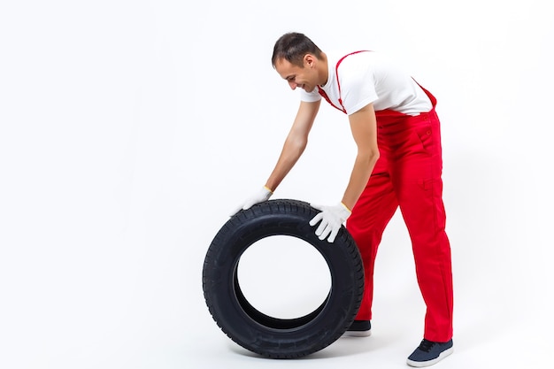Mécanicien tenant un pneu au garage de réparation. remplacement des pneus hiver et été.
