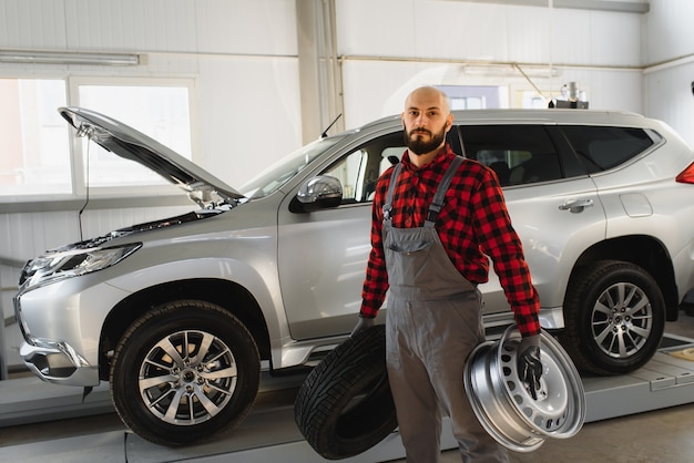 Mécanicien tenant un pneu au garage de réparation