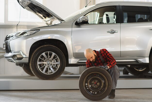 Mécanicien tenant un pneu au garage de réparation