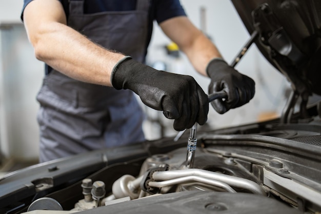 Mécanicien travaillant sur un moteur de voiture dans un atelier de garage de service