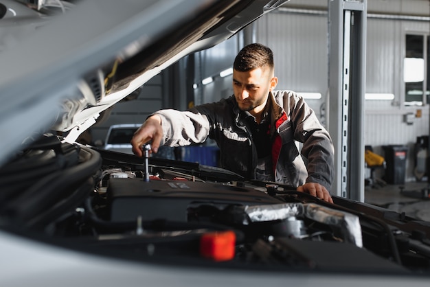 Mécanicien travaillant et tenant la clé de l'ordre de service pour l'entretien de la voiture