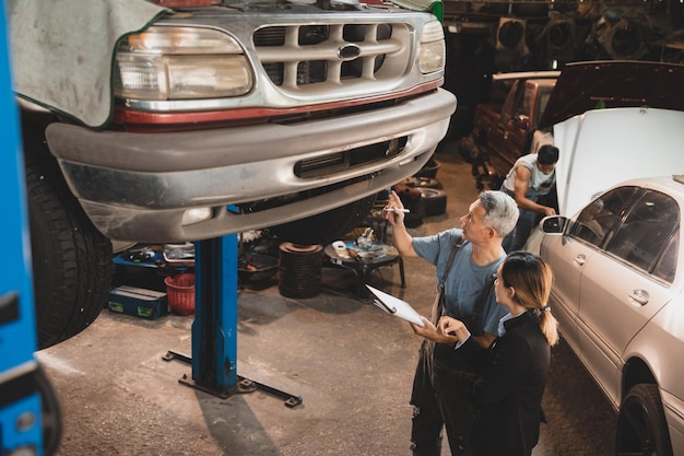 Mécanicien travaillant et vérifiant le technicien d'inspection de service de moteur de voiture automobile ayant un travail automobile pour entretenir ou réparer une automobile dans un garage automobile moteur de voiture automobile industriel