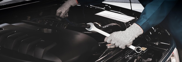 Photo le mécanicien travaille sur le moteur de la voiture dans le garage, le service de réparation automobile.